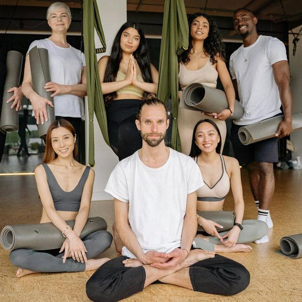 Group of women sitting in a circle and smiling in a yoga studio.
